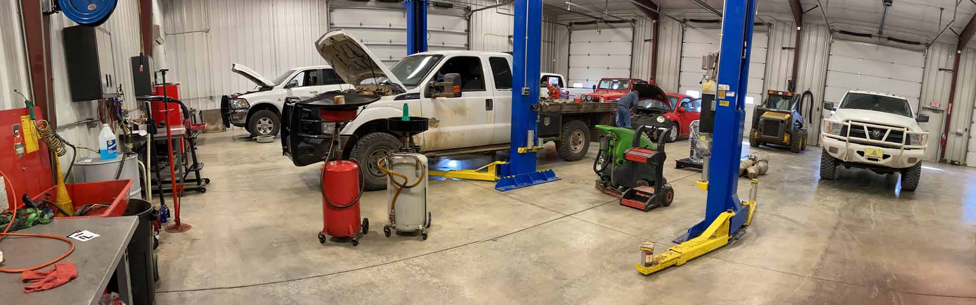 Diesel truck repair shop with pickups, a Volkswagon & a Jeep in various states of repair, including several with their hoods open
